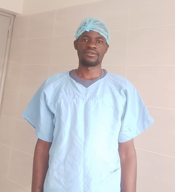 A clinician in surgical scrubs and cap on a hospital ward