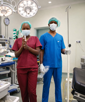Two clinicians in scrubs preparing an operating theatre
